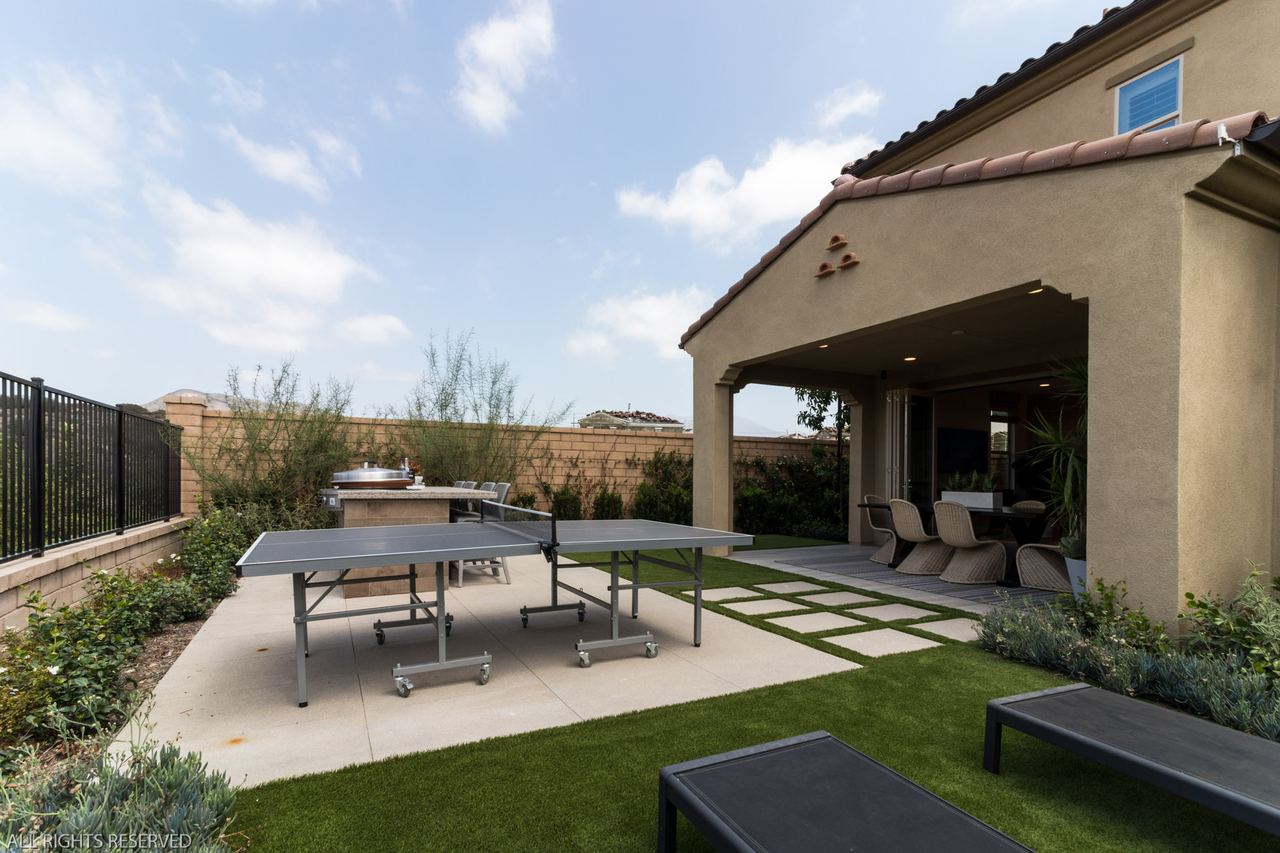 Backyard with a covered patio, ping-pong table and lawn