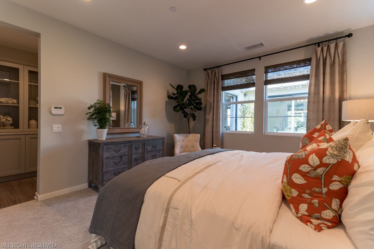 Warm neutral bedroom with layered pillows and window light