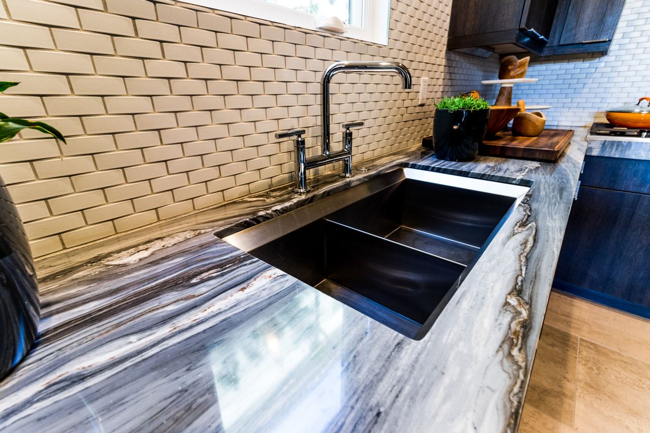 Detail of a marble countertop, brass faucet and tile backsplash