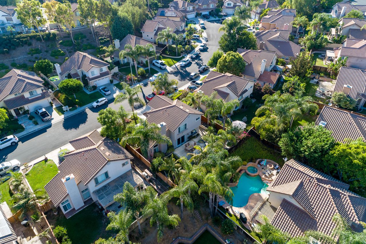 Overhead drone view of a residential neighborhood with pools