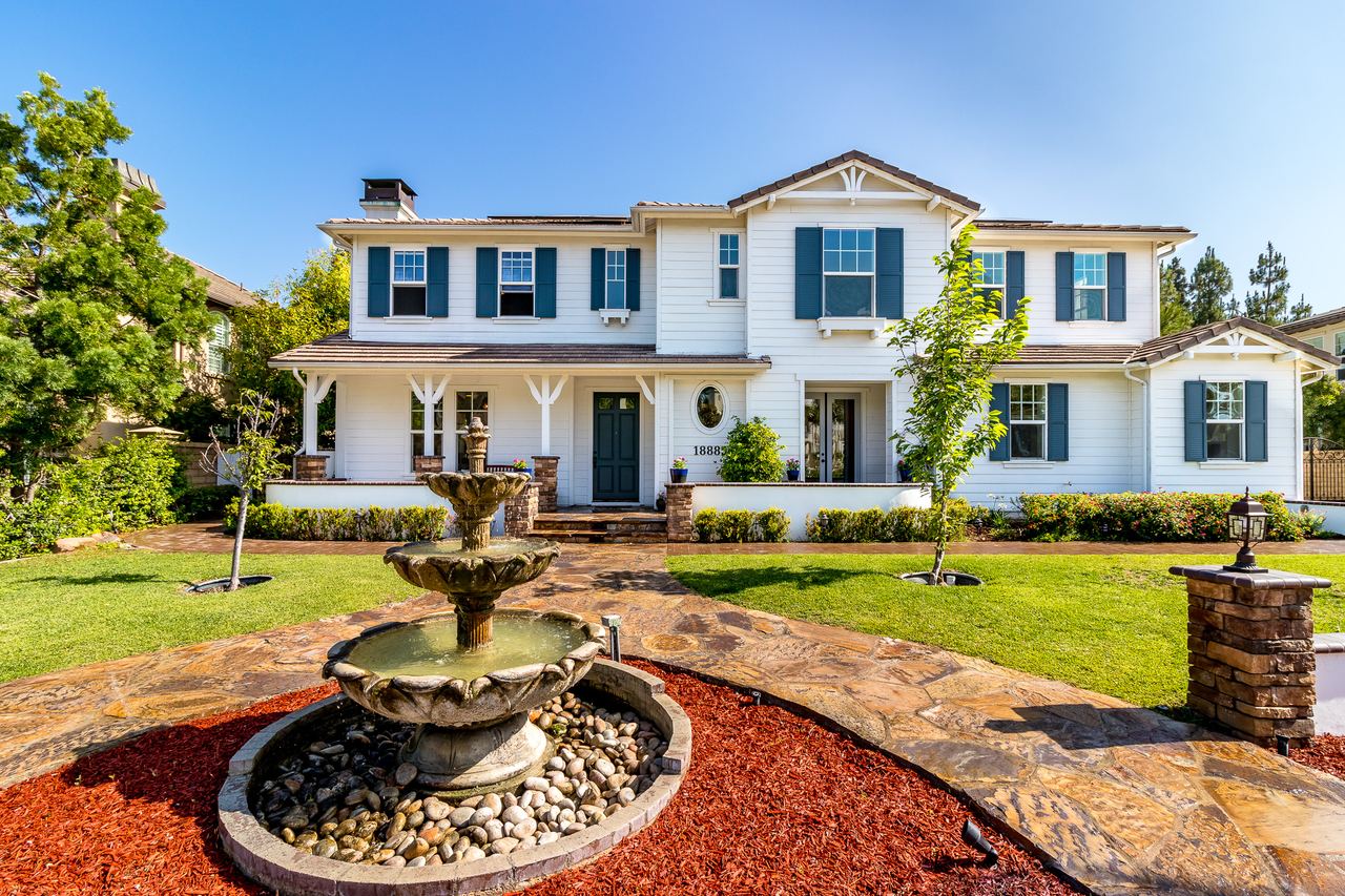 White estate home with a circular fountain in the front yard