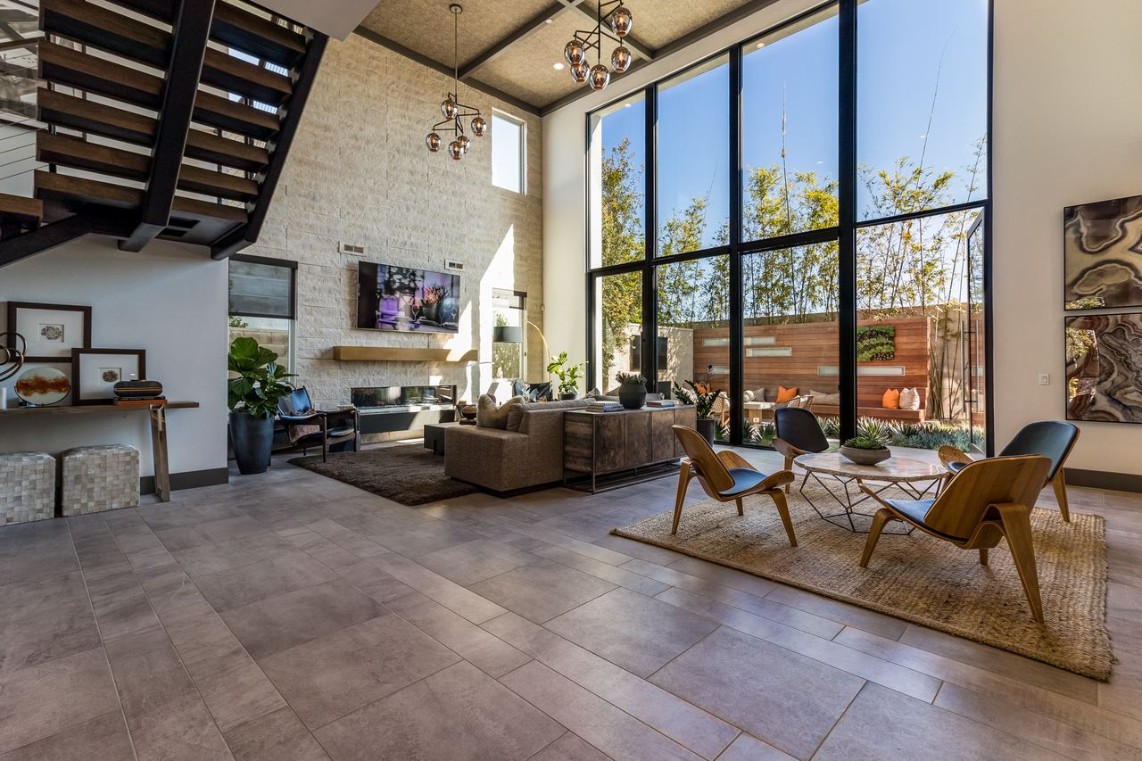 Double-height great room with floor-to-ceiling windows and mid-century lounge chairs
