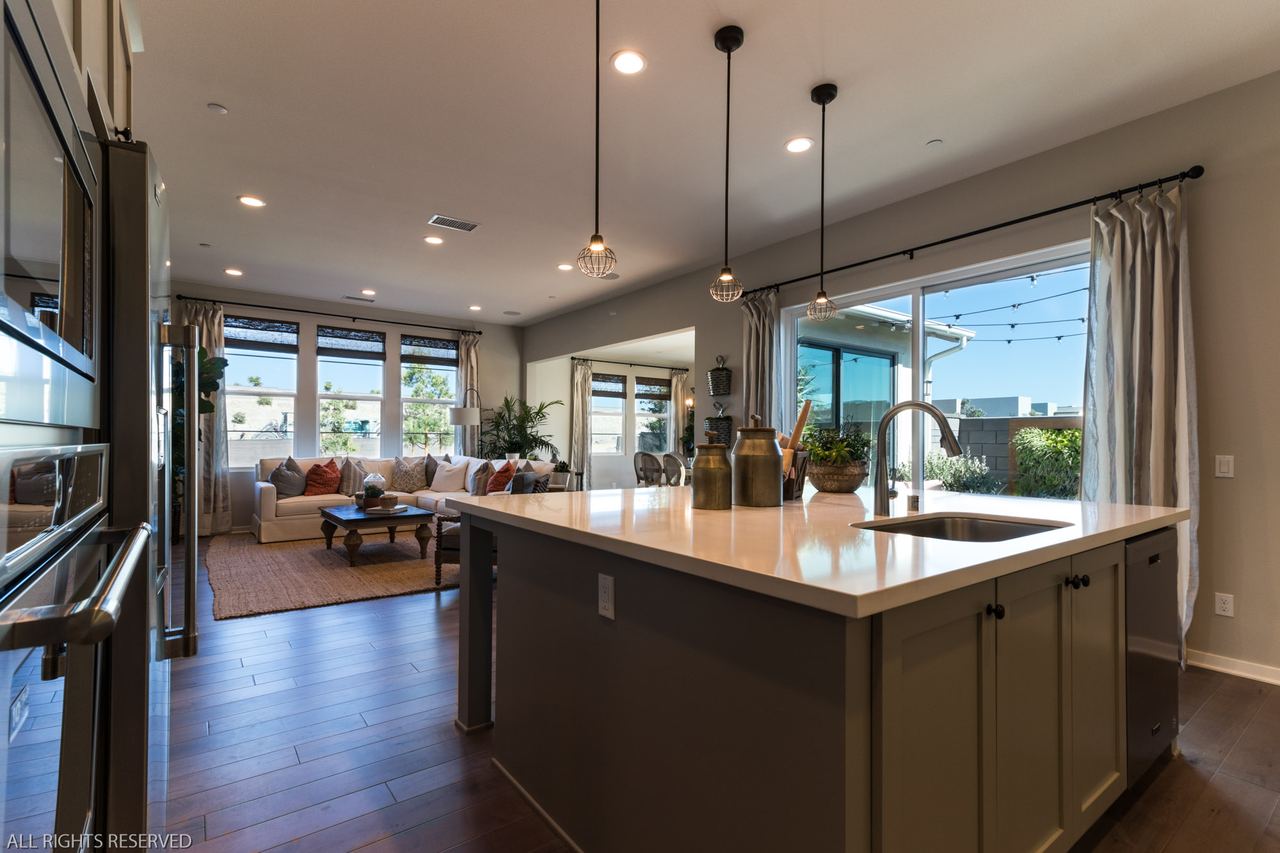 Gray kitchen island with pendant lighting and white cabinetry