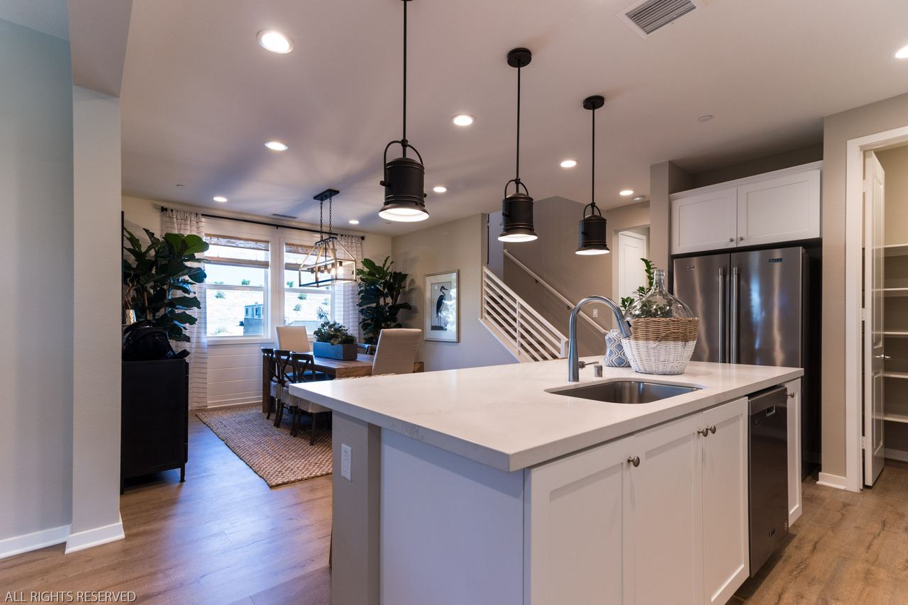 Kitchen island with pendant lights opening into the great room