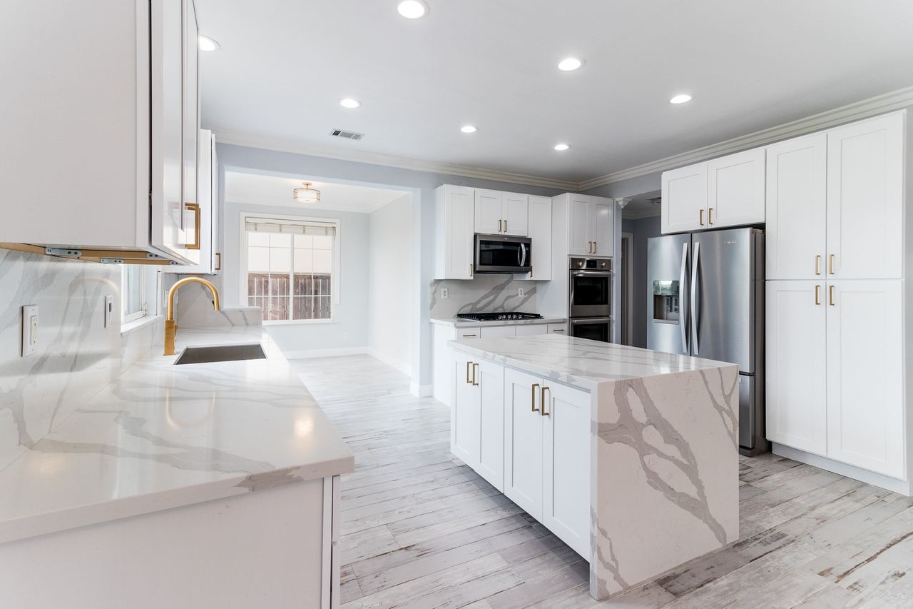 White kitchen with marble counters and a large island