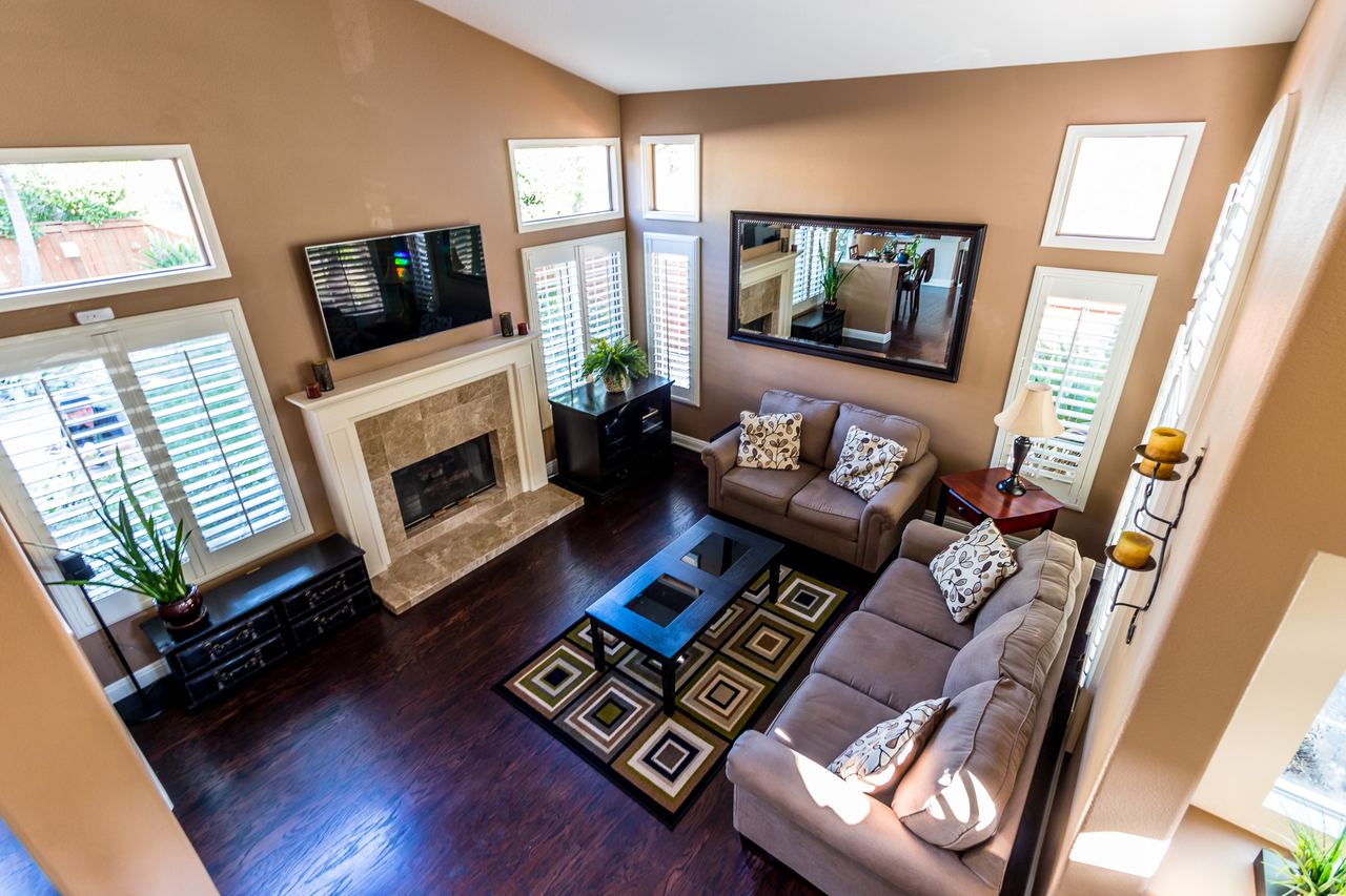 Living room with a fireplace, hardwood floors and high windows