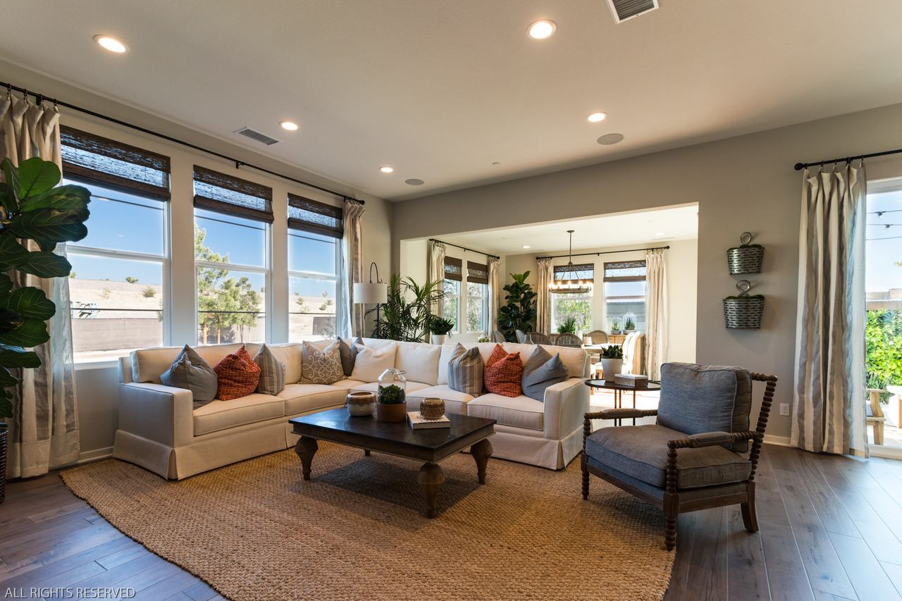 Sunlit living room with a white sectional and a view into the dining room