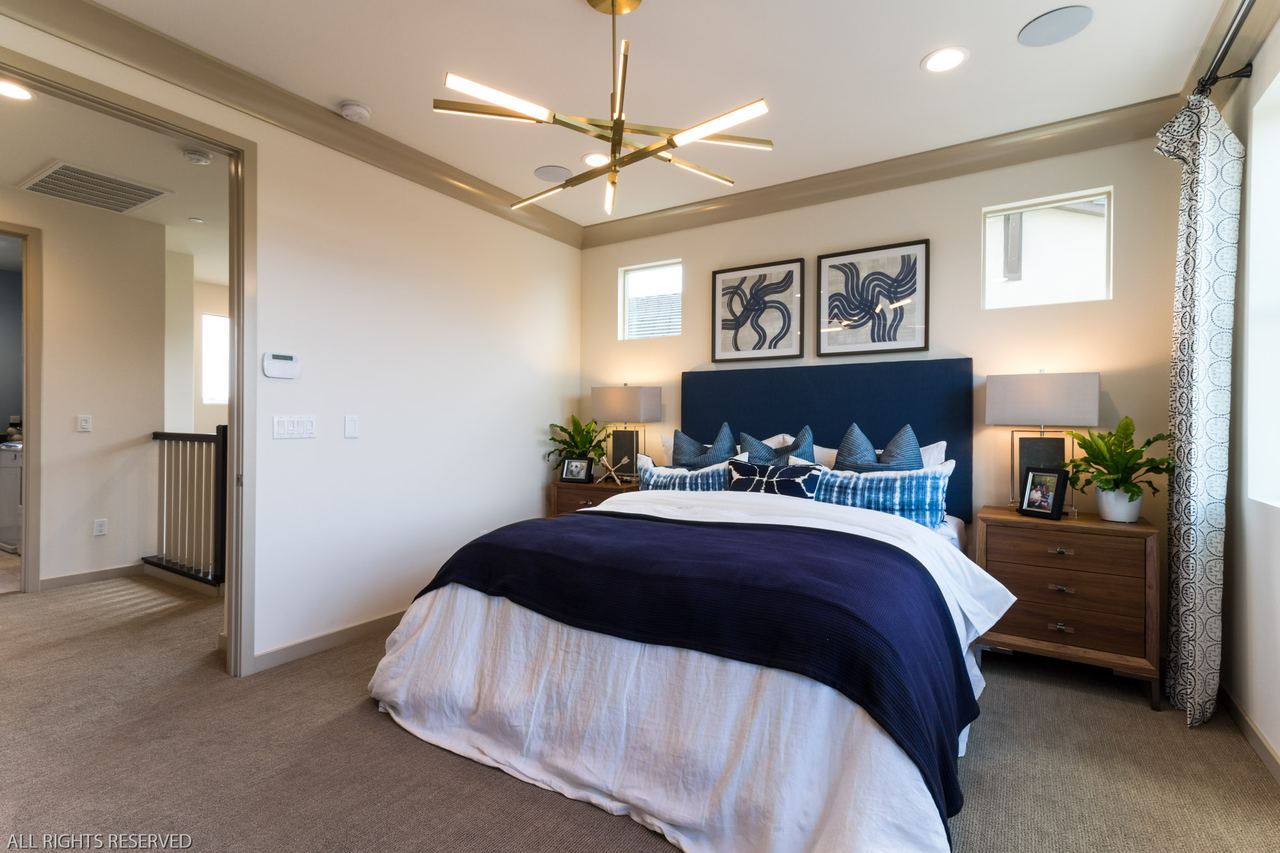 Primary bedroom with a navy headboard, gallery wall and ceiling fan